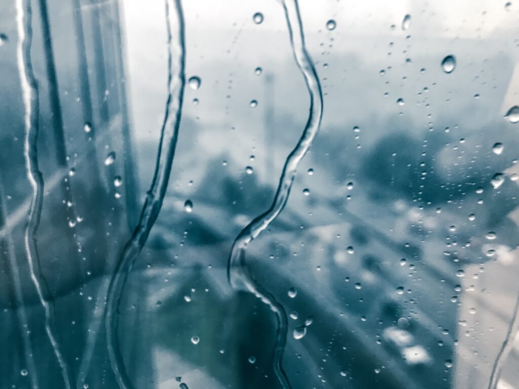 Rain. Window. Glass. Water drops. Urban. Weather. Moody.